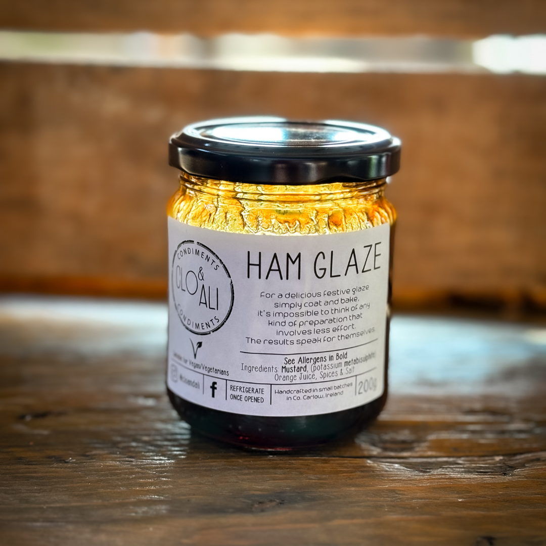 A jar of Ham Glaze with a label on the front, placed on a wooden surface with a wooden background.
