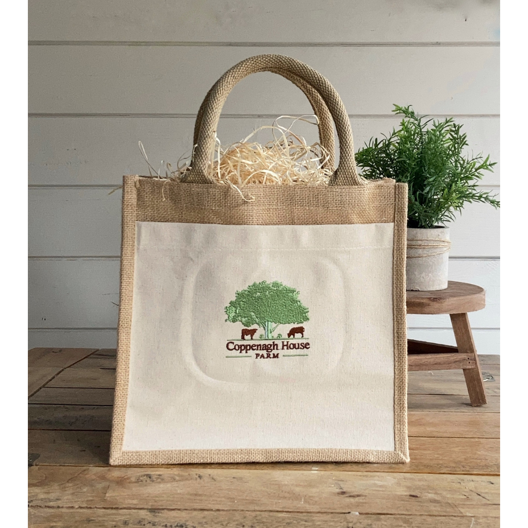 Jute tote bag with a visible brand logo on a wooden surface