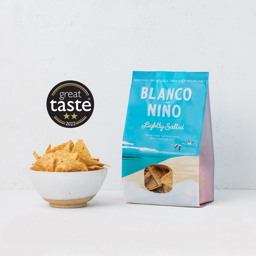 Bag of crisps beside a bowl of crisps on a white background