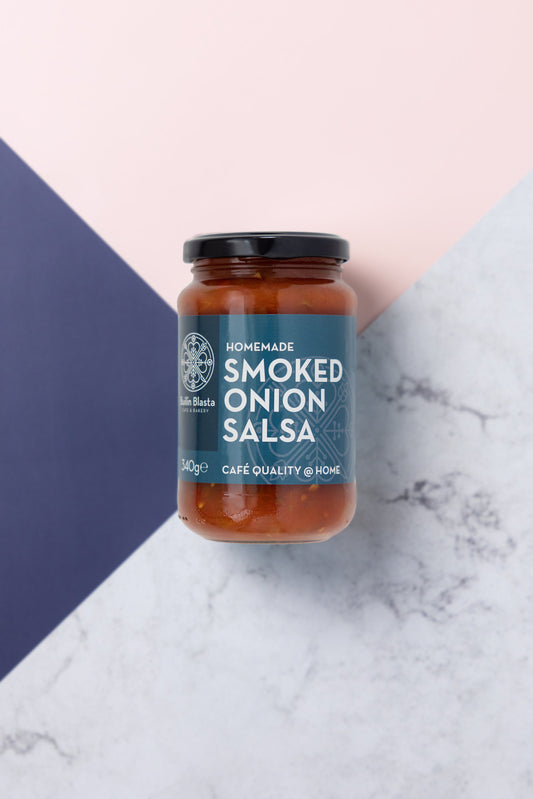 A jar of Smoked Onion Salsa placed on a two-tone background, with blue on one side and a white marble effect on the other.