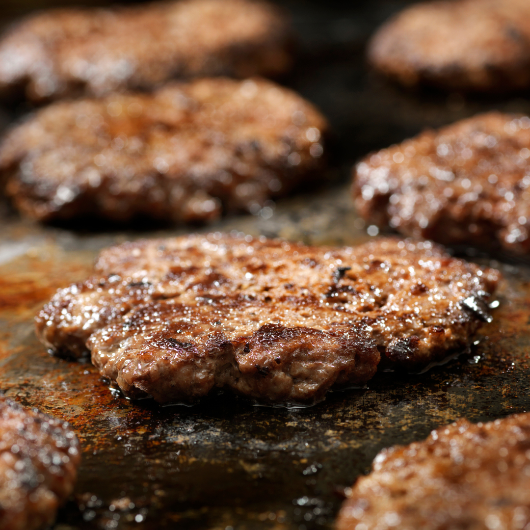 Smash burgers being cooked on an oily surface