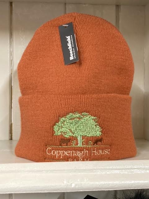 A coral beanie hat with an embroidered logo on the front.