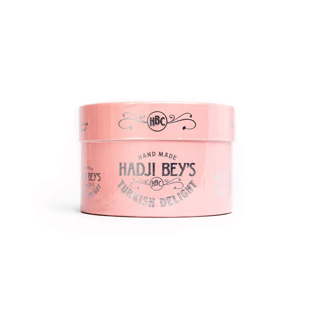 A pink box of Hadji Beys Turkish Delight placed on a wooden surface with a white background.