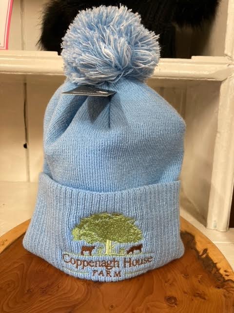 A light blue bobble hat with an embroidered logo on the front.