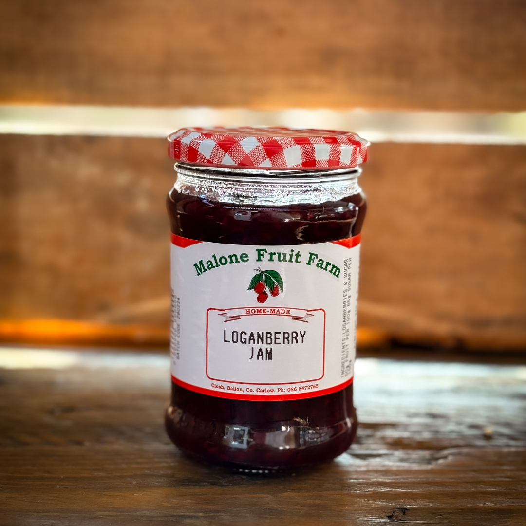 A jar of Malone's Fruit Farm Loganberry jam with a red and white checkered pattern on the lid, placed on a wooden surface.