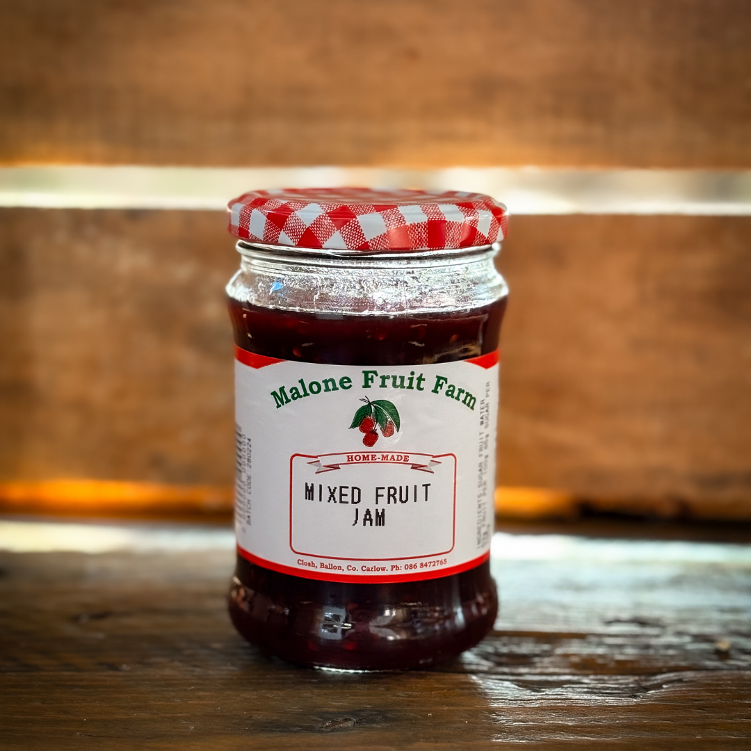 A jar of Malone's Fruit Farm mixed fruit jam with a red and white checkered pattern on the lid, placed on a wooden surface.