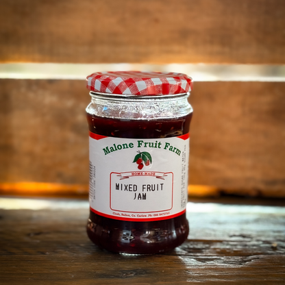 A jar of Malone's Fruit Farm mixed fruit jam with a red and white checkered pattern on the lid, placed on a wooden surface.