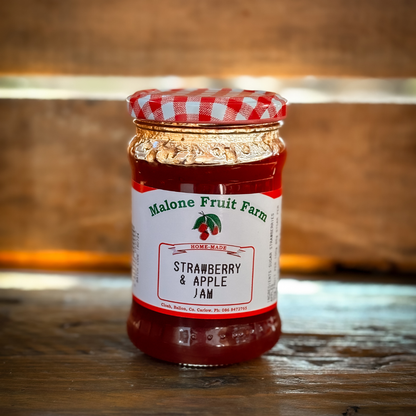 A jar of Malone's Fruit Farm strawberry and apple jam with a red and white checkered pattern on the lid, placed on a wooden surface.