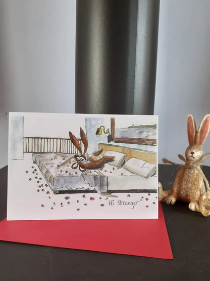 Card with a rabbit on a bed covered in rose petals