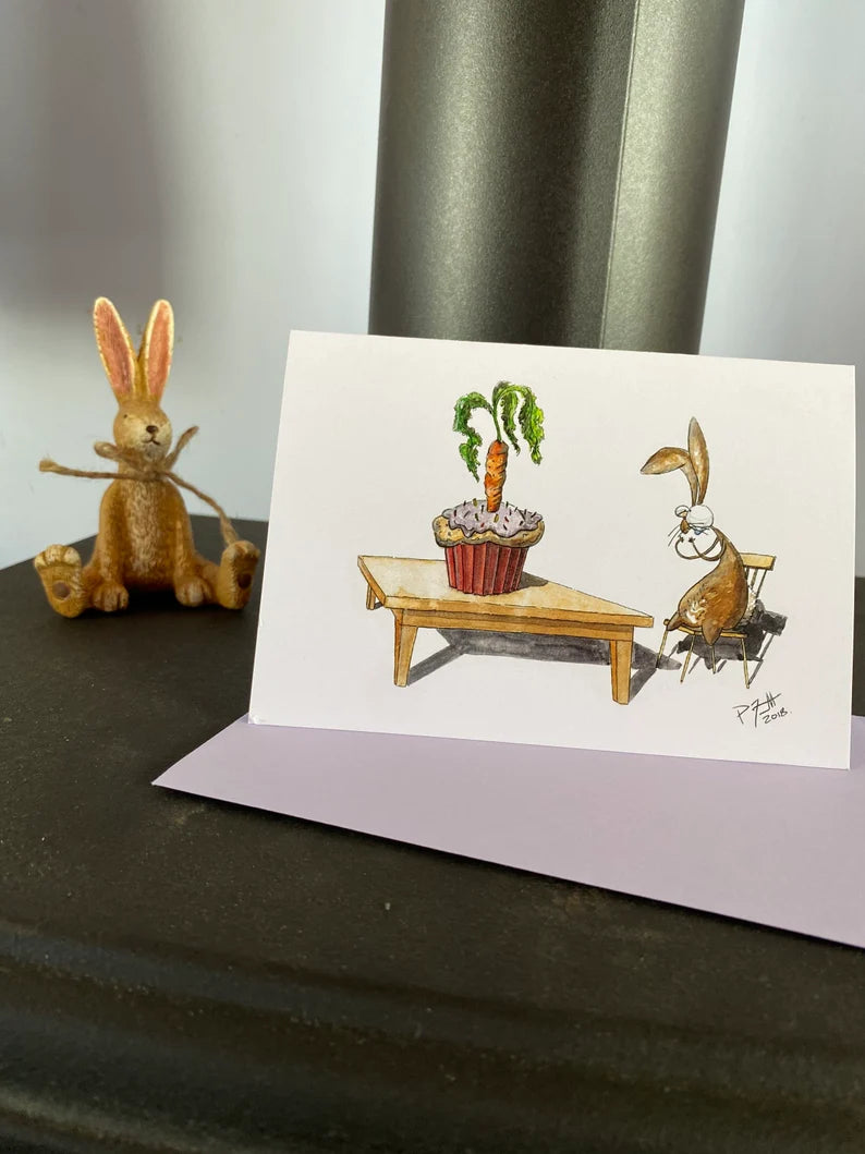 Card with a rabbit looking at a birthday carrot cupcake