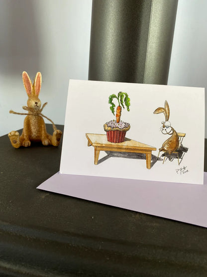 Card with a rabbit looking at a birthday carrot cupcake