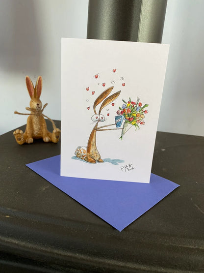 Card with a rabbit holding a bouquet of flowers and a box of chocolates